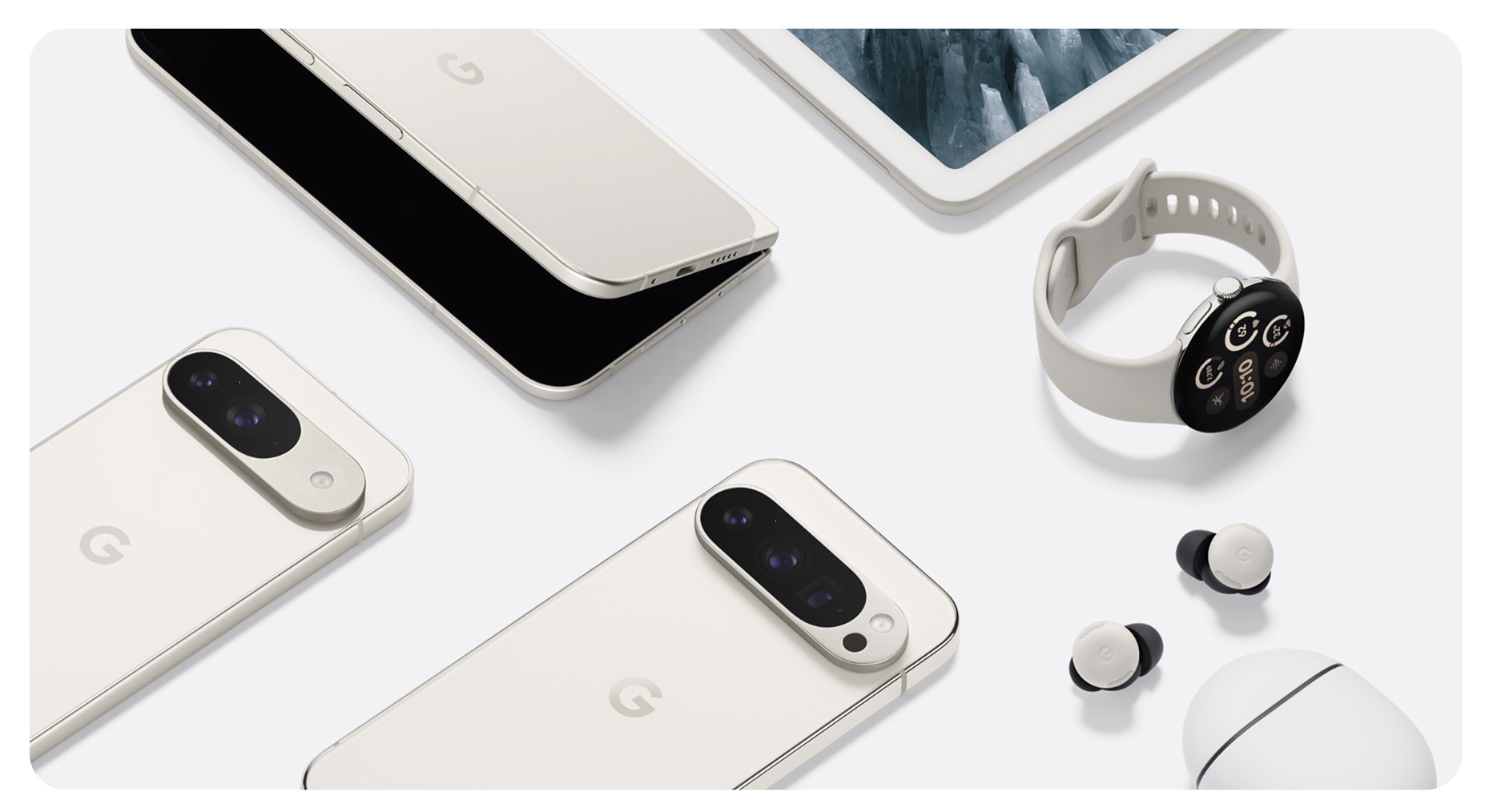 Overhead product shot of Pixel phones, a foldable, a tablet, a watch and earbuds with case on a pale surface.